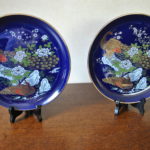 2 wandbordjes (blauw met gouden rand; afbeelding "pauwen")