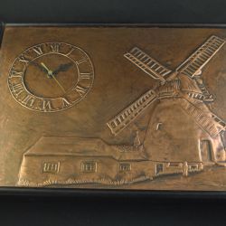 Ingelijst koperrelief (van een molen) met wandklok